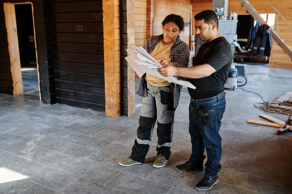 Two contractors discussing plans inside a home under construction