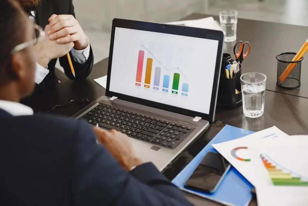 Two professionals reviewing a business graph on a laptop during a meeting