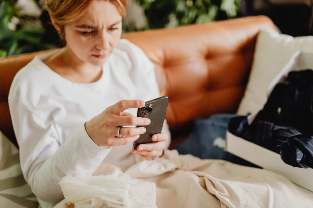 Woman on a couch reading online reviews on her smartphone